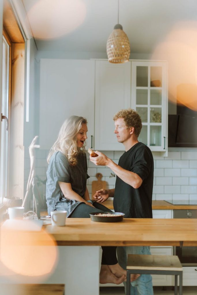A couple enjoys a warm moment sharing pie in their stylish kitchen. Perfect for lifestyle inspiration.